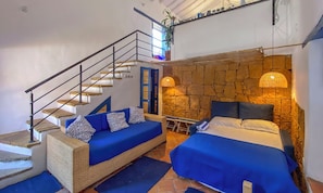 Ein Schlafzimmer mit einem Bett, einer Couch, einer Treppe und einer Steinwand.