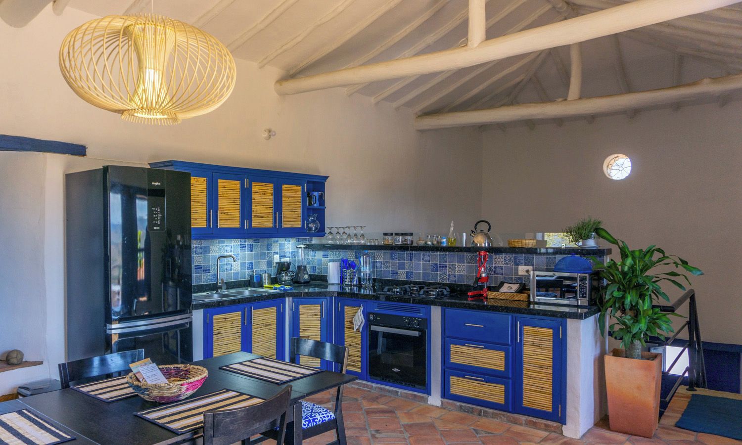 Una cocina con armarios azules, una estufa a gas y una lámpara colgante.