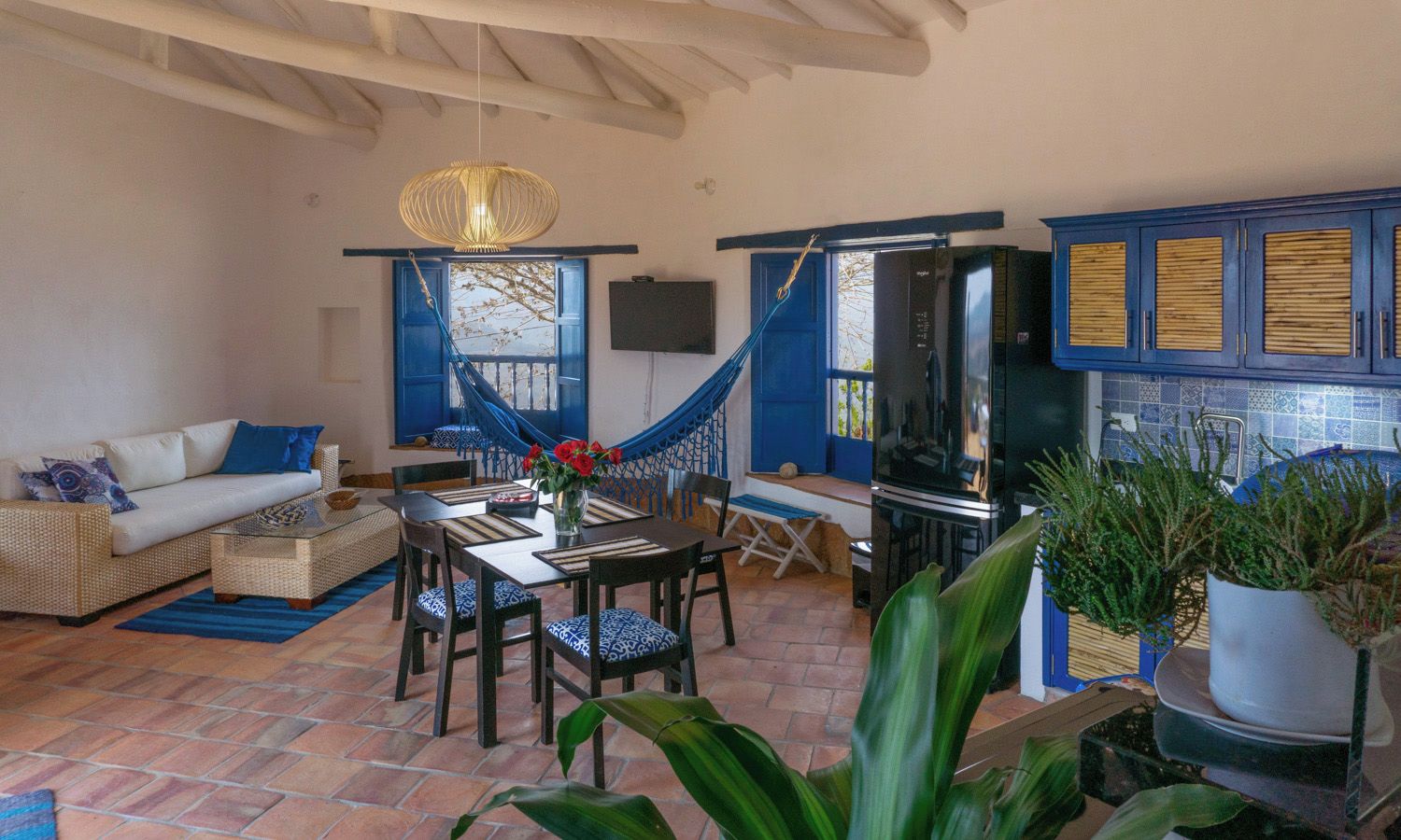 Una sala de estar con sofá, mesa de comedor, sillas, televisor y una escalera azul.