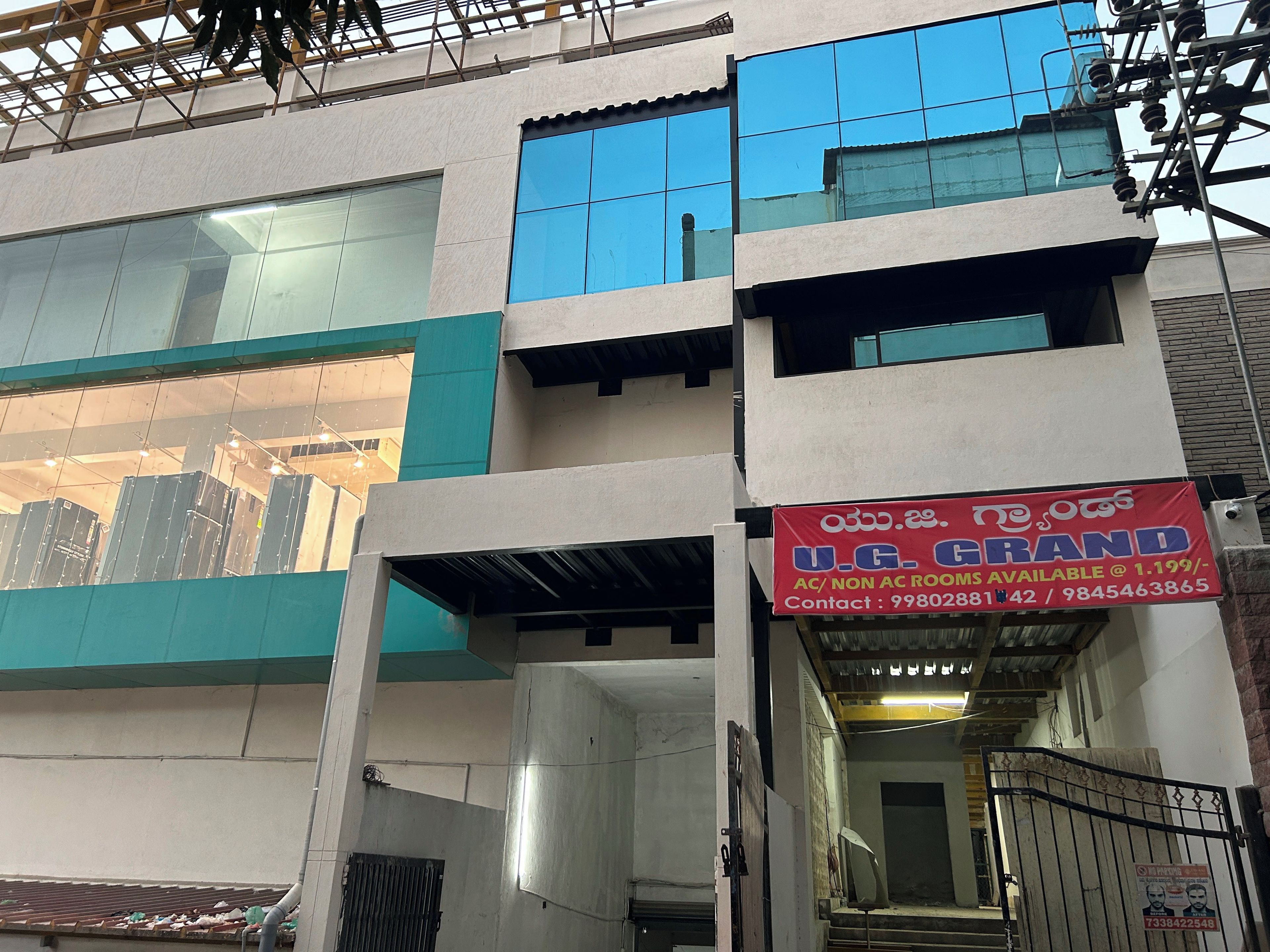 A multi-story building with a signboard advertising U.G. GRAND AC/NON AC rooms.