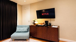 Ein modernes Wohnzimmer mit einer Couch, einer Kaffeestation und einem Flachbildfernseher, der das Netflix-Logo zeigt.