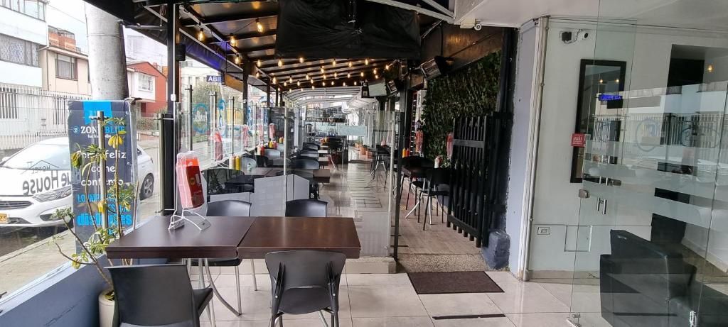 Een terras met tafels en stoelen, een glazen wand en uitzicht op de straat.
