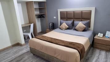 Ein Schlafzimmer mit einem Bett, Nachttischen, einem Kleiderschrank und einem Schreibtisch.