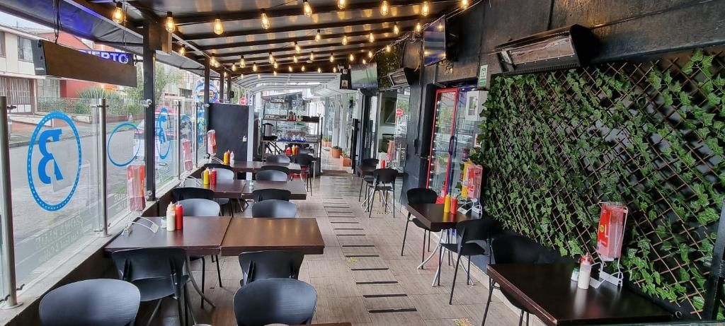 Een eetgedeelte met tafels en stoelen, een keuken op de achtergrond, en een wand met weelderig groen.