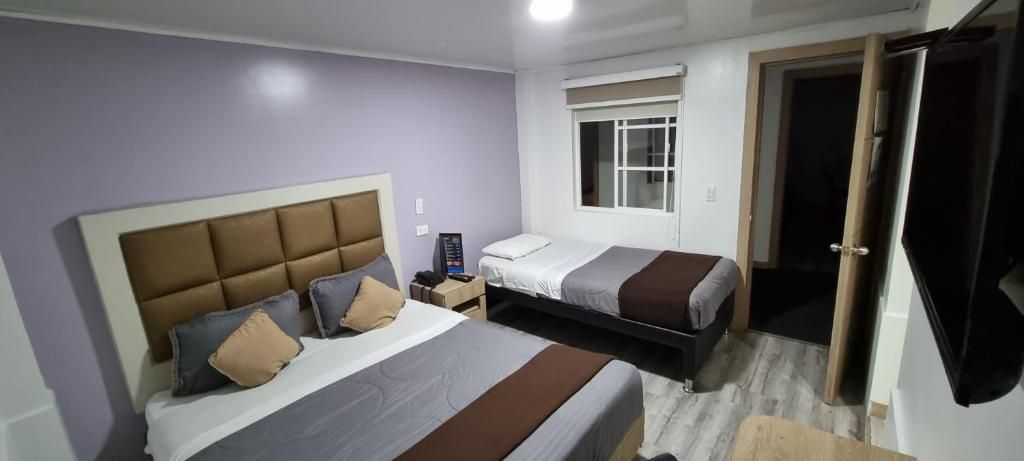 Een slaapkamer met twee bedden, een nachtkastje en een raam.