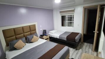Een slaapkamer met twee bedden, een nachtkastje en een raam.