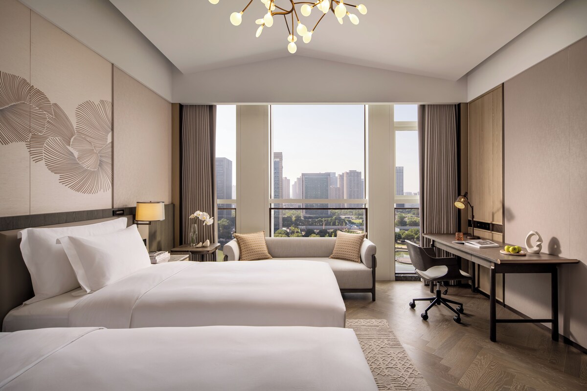 Una habitación de hotel con una cama grande, un escritorio, una silla y vistas a la ciudad.