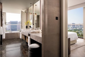 Un baño moderno con un espejo grande, lavamanos dobles y vistas a la ciudad.