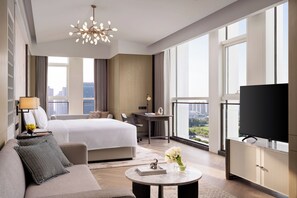 Una habitación de hotel moderna con una cama grande, un sofá, un escritorio, un televisor y vistas a la ciudad.