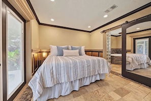 Un dormitorio con una cama grande, una mesita de noche, un espejo y vistas a un baño con bañera.