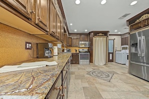 A kitchen with marble countertops, stainless steel appliances, and wooden cabinetry. - Pelican Pointe - a 2BR part of a duplex that sleeps 6 (Pensacola)
