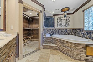 Un baño espacioso con una bañera grande, ducha a pie y tocador con espejo.