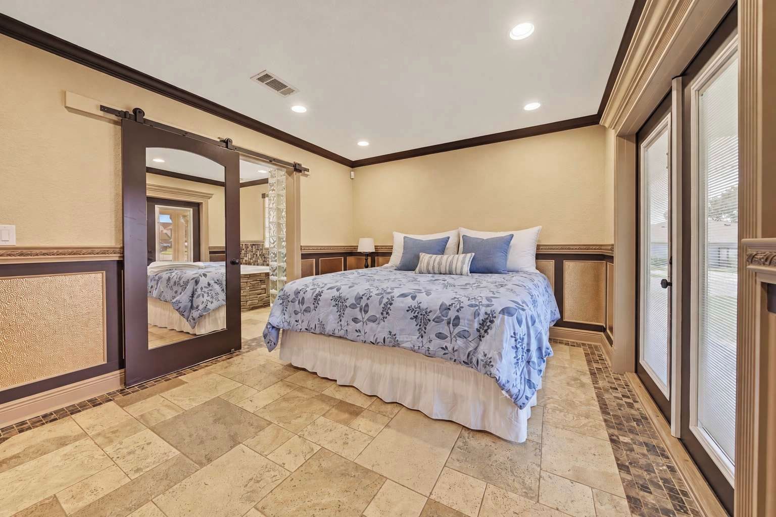 Un dormitorio con una cama grande, un espejo y una puerta corredera que da a un baño.