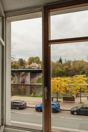 A view through a window of a street with cars, a bridge, and trees. - Old Town Riverside Apartment, Retro Vibe & River Panorama (Vilnius)