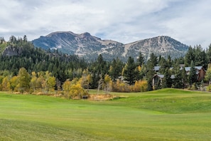 A golf course with a view of mountains and a forested area. - Communal Hot Tub | Fireplace (Mammoth Lakes)