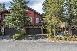 A two-story house with a stone foundation, red siding, and a black garage door. - Communal Hot Tub | Fireplace (Mammoth Lakes)