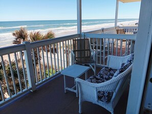 A balcony with a view of the beach, white wicker furniture, and a small table. - Oceanfront 1 bdrm w/balcony, pool, hot tub & more (Daytona Beach)