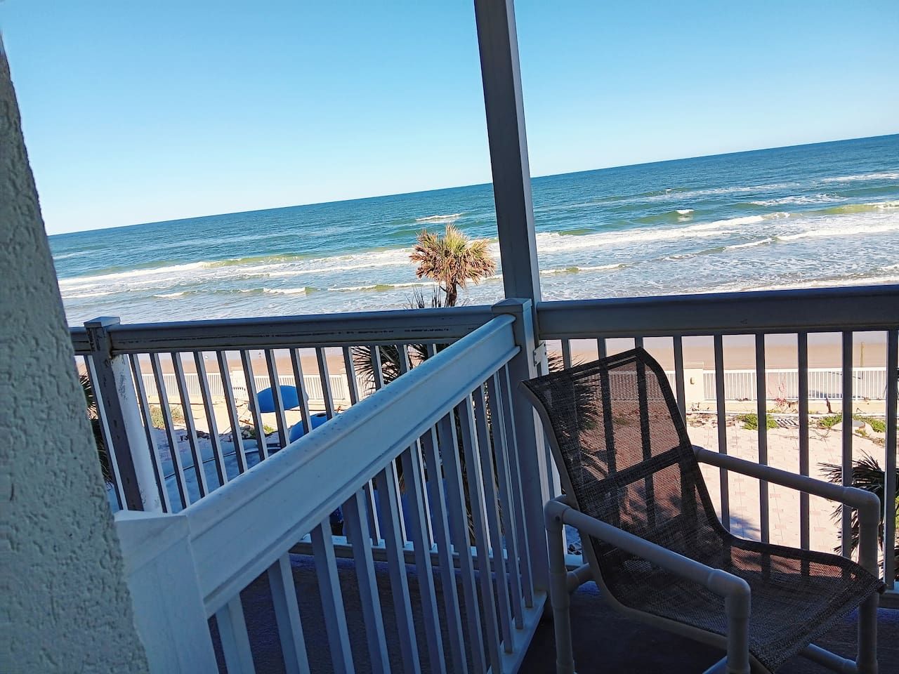 A balcony with a view of the beach and ocean.