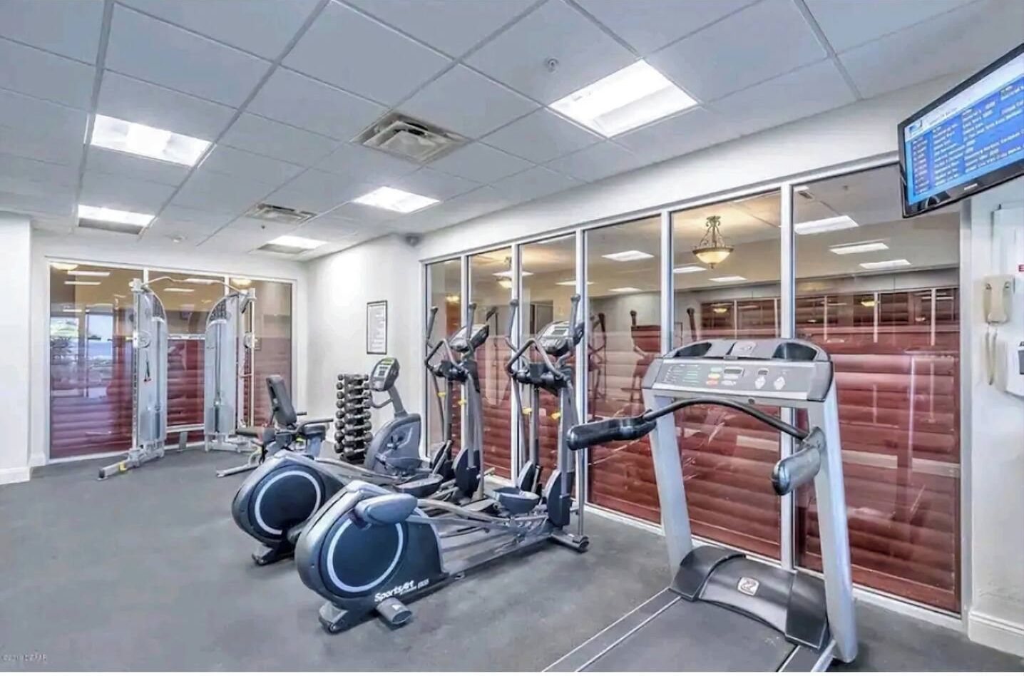 Bright on-site fitness room with cardio machines, weights, and workout space