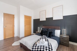 A modern bedroom with a large bed, wooden doors, and artwork on the walls. - Modern Luxury Apartment City Centre (Birmingham)