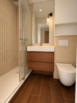 A modern bathroom with a glass shower enclosure, a wooden vanity, and a white toilet. - New Listing (Paris)