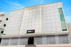 Edifici d'hotel amb façana de disseny en forma de retícula, un senyal que indica 'OYO Hotel' i un conjunt de persianes tancades a la planta baixa.