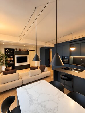 A modern kitchen with a built-in oven, a dining area with a marble table, and a living room with a sofa and a TV. - Apartment in the City Centre 'Vittorio Amedeo II Apartment' (Torino)