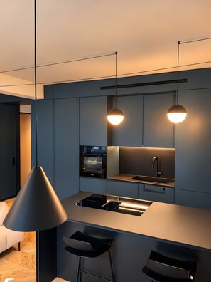 A modern kitchen with a central island, pendant lighting, and built-in appliances. - Apartment in the City Centre 'Vittorio Amedeo II Apartment' (Torino)