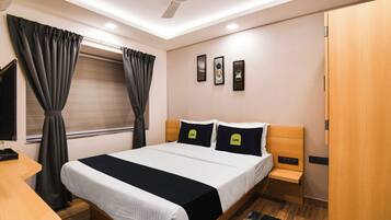 A modern hotel room with a bed, bedside tables, a desk, a ceiling fan, and a window with curtains.