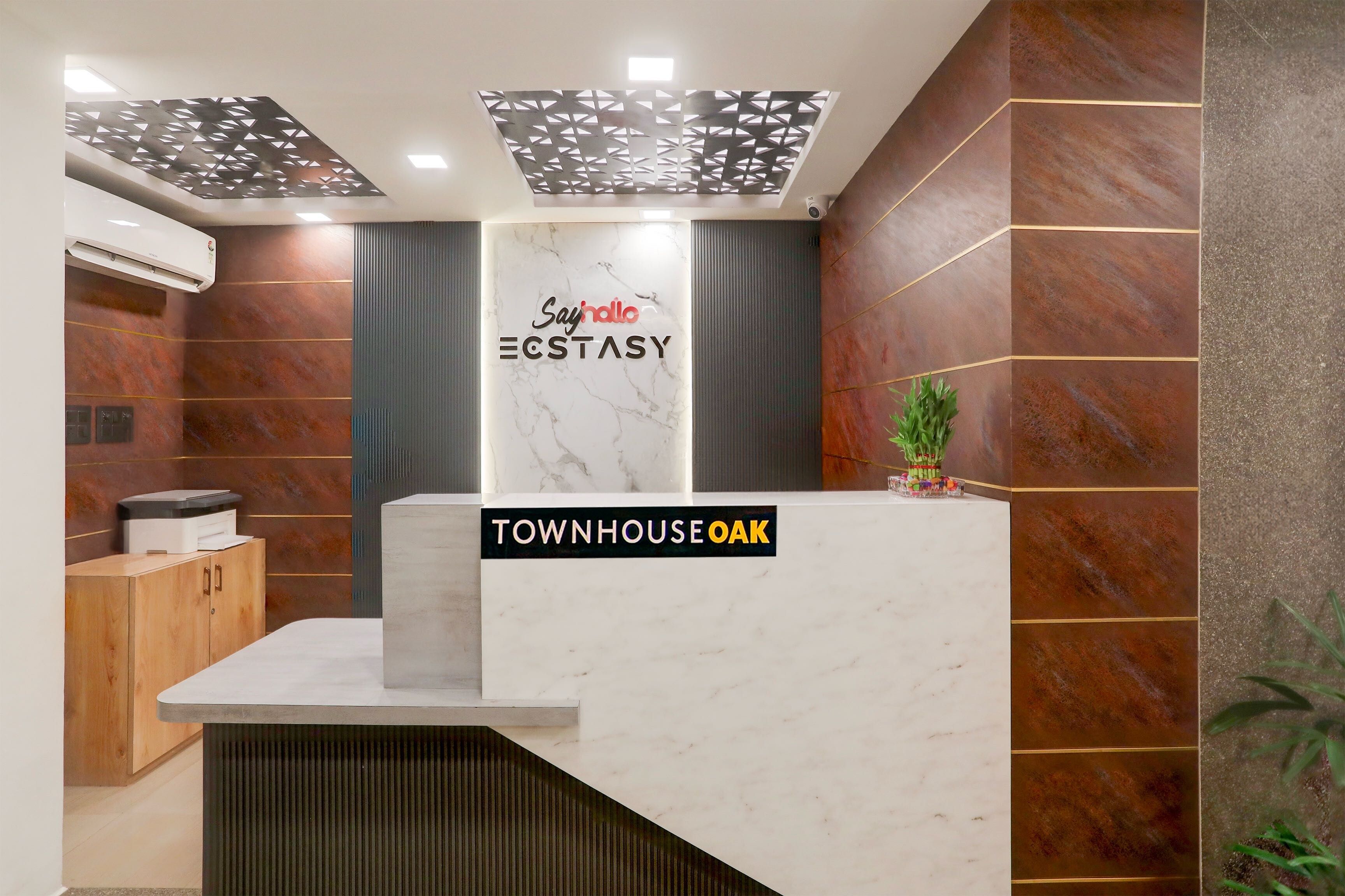 A reception desk with a 'Say hello' sign, a 'TOWNHOUSE OAK' label, and a security camera.
