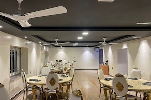 A dining area with round tables, chairs, ceiling fans, and recessed lighting. - Townhouse Oak Sayhallo Ecstasy (Bhubaneswar)