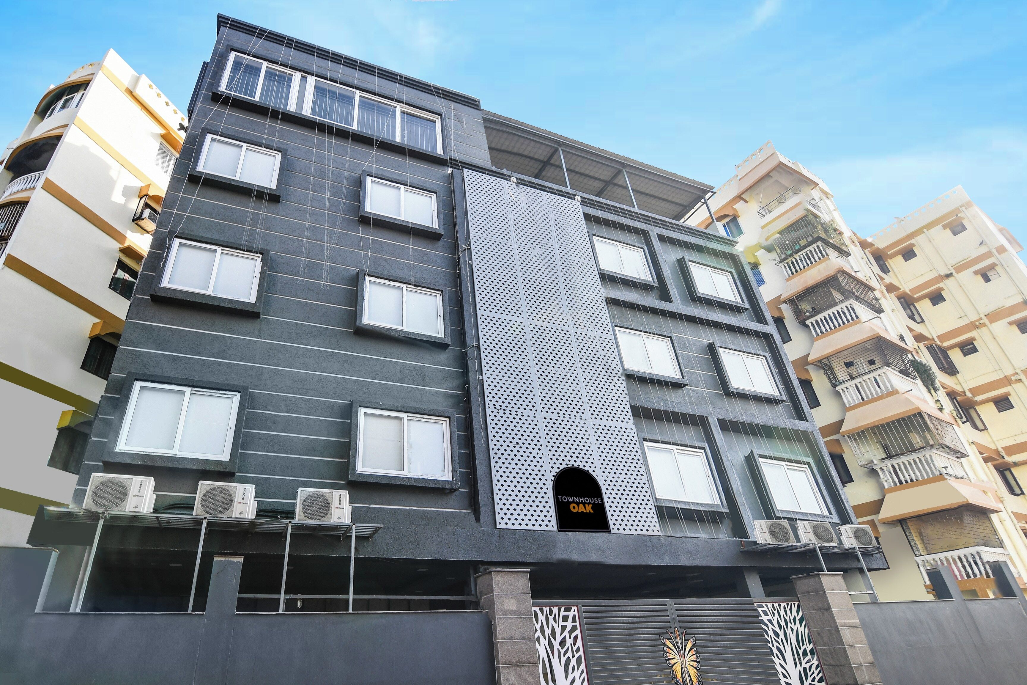 A multi-story building with a modern facade, air conditioning units, and a prominent vertical design element.