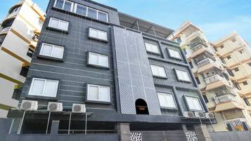 A multi-story building with a modern facade, air conditioning units, and a prominent vertical design element.
