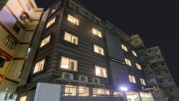 Un edificio de varios pisos con ventanas iluminadas y unidades de aire acondicionado.