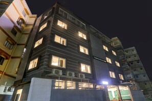Un edificio de varios pisos con ventanas iluminadas y unidades de aire acondicionado.