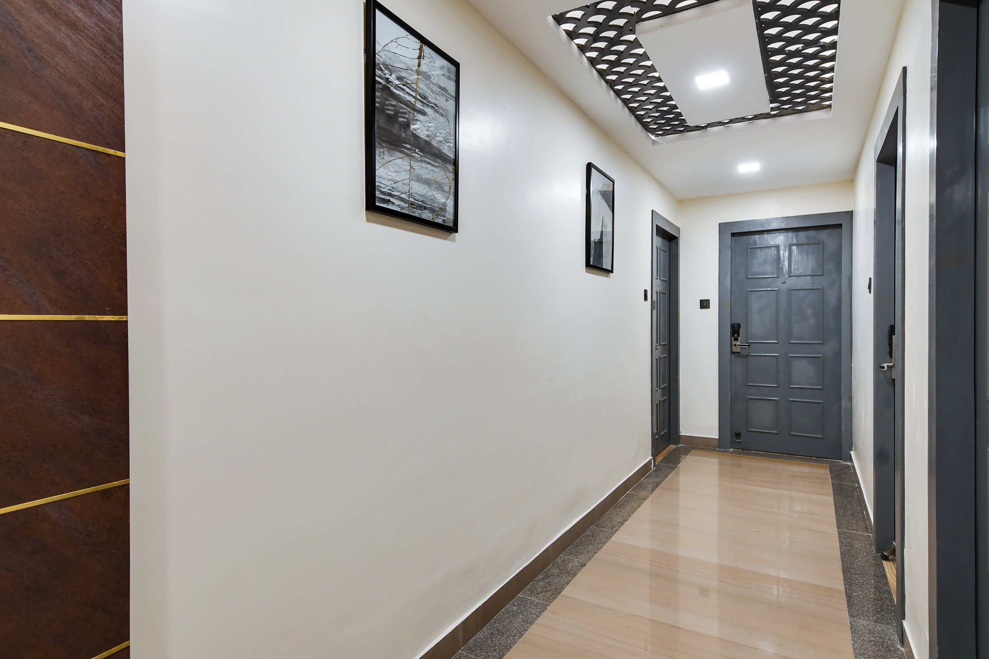 A hallway with a wooden panel on the left, a tiled floor, and a door at the end.