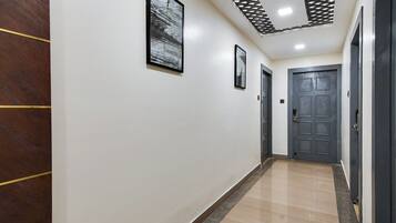 A hallway with a wooden panel on the left, a tiled floor, and a door at the end.