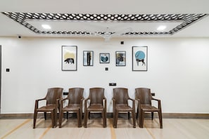 A waiting area with five brown chairs and four framed artworks on the wall.