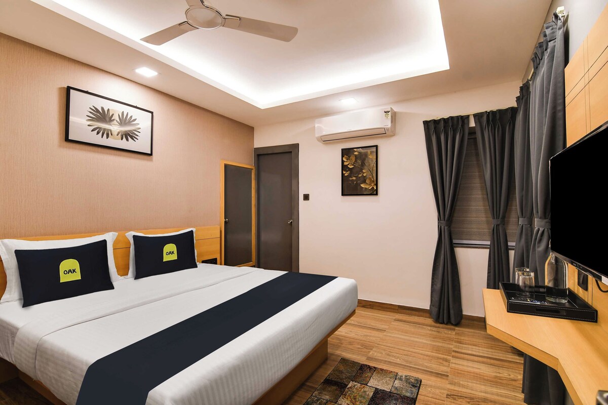 Una habitación de hotel con una cama, un televisor de pantalla plana, un equipo de aire acondicionado, un ventilador de techo y una ventana con cortinas.