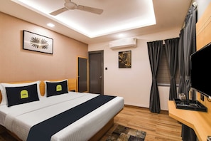 A hotel room with a bed, a flat-screen TV, an air conditioning unit, a ceiling fan, and a window with curtains. - Townhouse Oak Sayhallo Ecstasy (Bhubaneswar)