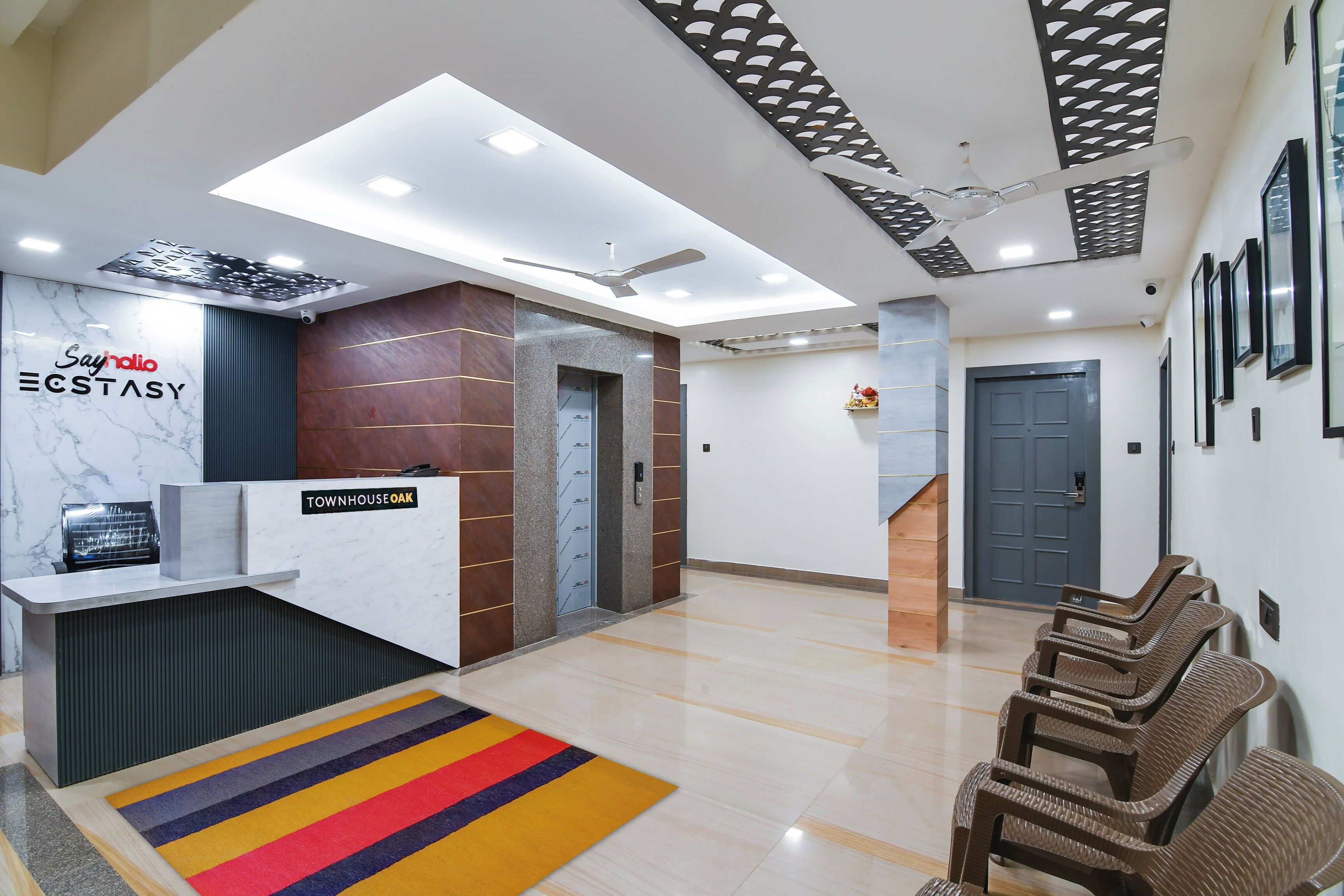 A reception area with a marble counter, a reception desk, a staircase, and a waiting area with chairs.