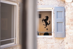 A room with a window, a wall-mounted sculpture of a horse, a small table, and a chair. - New Listing (Modena)