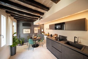 A modern kitchen with a built-in Bosch microwave, a sink, and a dining area with chairs and a table. - New Listing (Modena)