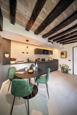 A modern kitchen with a dining area, featuring a round table with chairs, a hanging light fixture, and a built-in microwave. - New Listing (Modena)