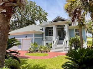 A two-story house with a front porch, a garage, and a well-maintained lawn. - Marsh View @ 162 (Fripp Island)