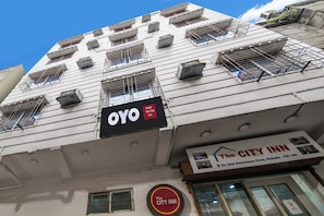 A building with multiple air conditioning units, a sign for 'OYO Hotel The City Inn,' and a sign for 'The City Inn' with an address. - Hotel O CITY INN (Kolkata)