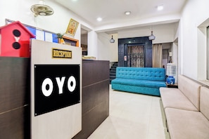 A reception area with a reception desk, a blue sofa, and a water dispenser. - Hotel O CITY INN (Kolkata)