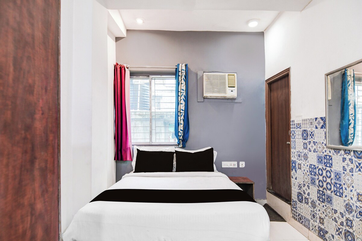 A bedroom with a bed, a window with curtains, an air conditioning unit, and a tiled wall.