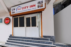 Entrada de un hotel con un cartel que muestra el nombre 'The City Inn' e información de contacto.