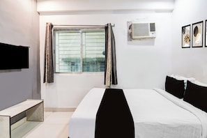 A hotel room with a bed, a TV mounted on the wall, a window with curtains, an air conditioning unit, and a small bedside table. - Hotel O CITY INN (Kolkata)